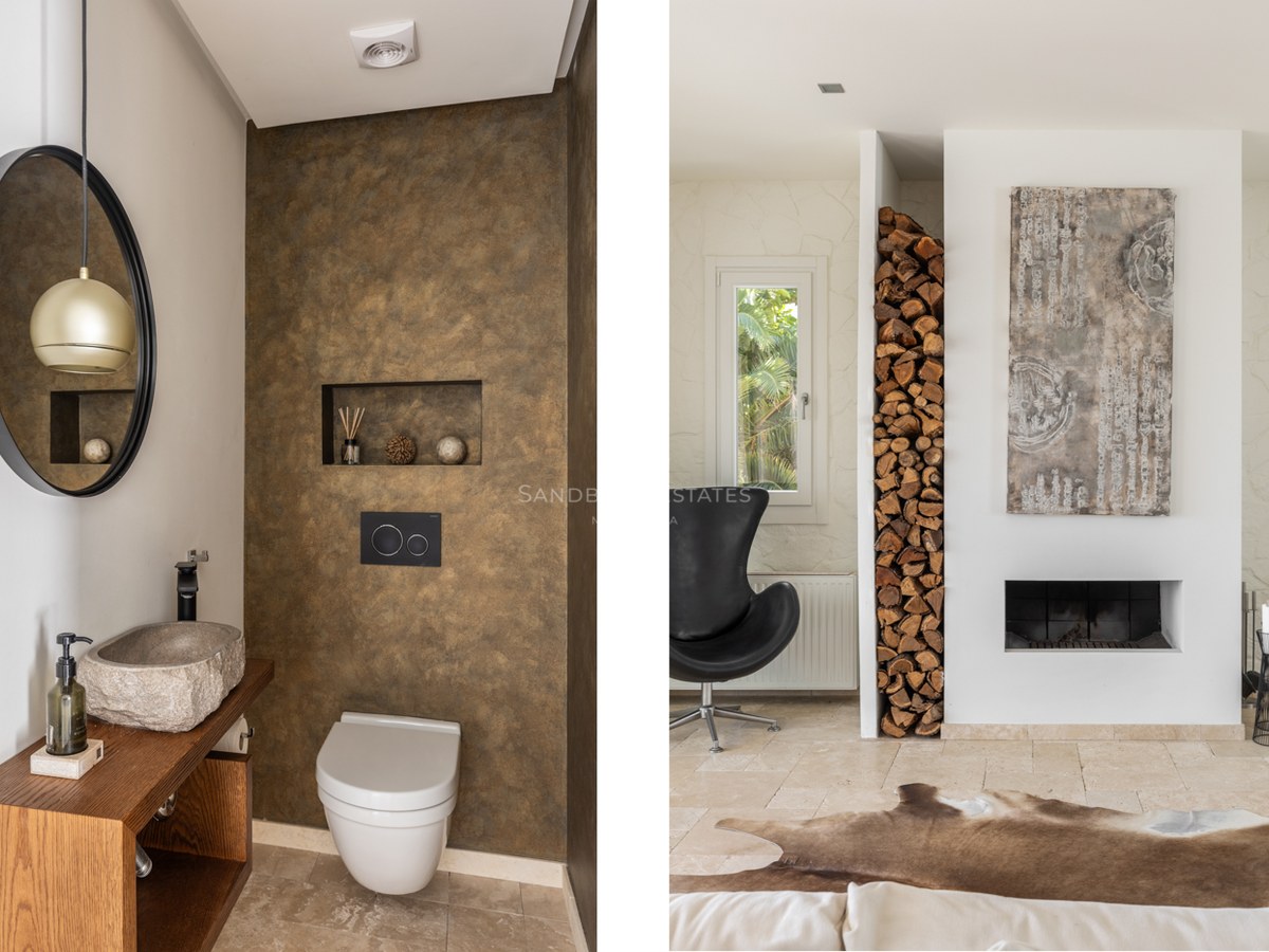 Salle d'eau avec vasque en pierre et salon avec cheminée minimaliste et niche à bois.