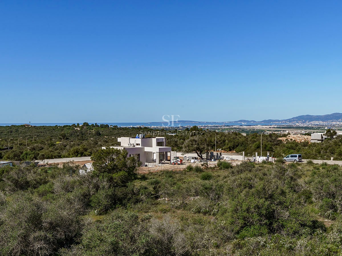 Vue extérieure d'une villa contemporaine blanche en construction surplombant la côte méditerranéenne.