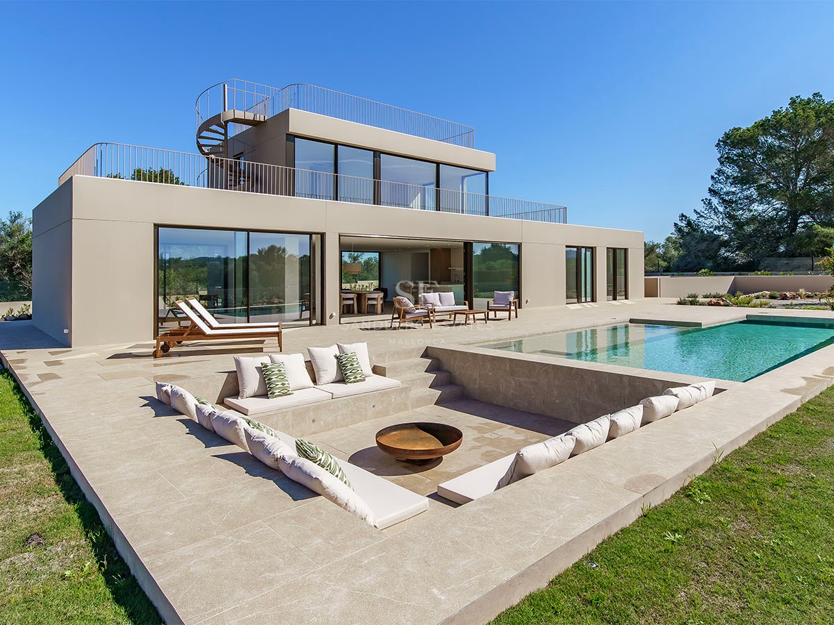 Villa moderne de deux étages avec façade couleur sable, piscine et salon de jardin encastré avec brasero.