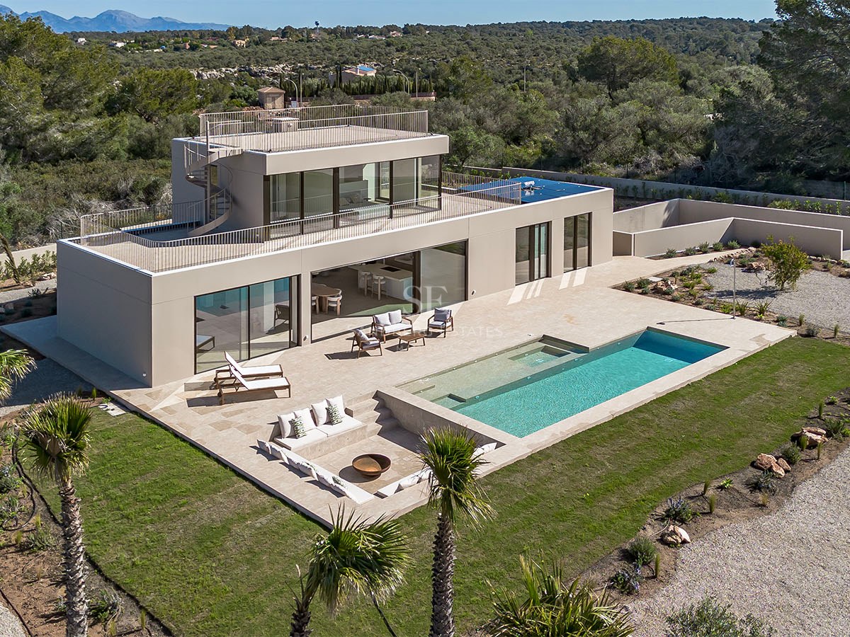 Vue aérienne d'une villa moderne avec piscine, terrasse et salon extérieur encastré.