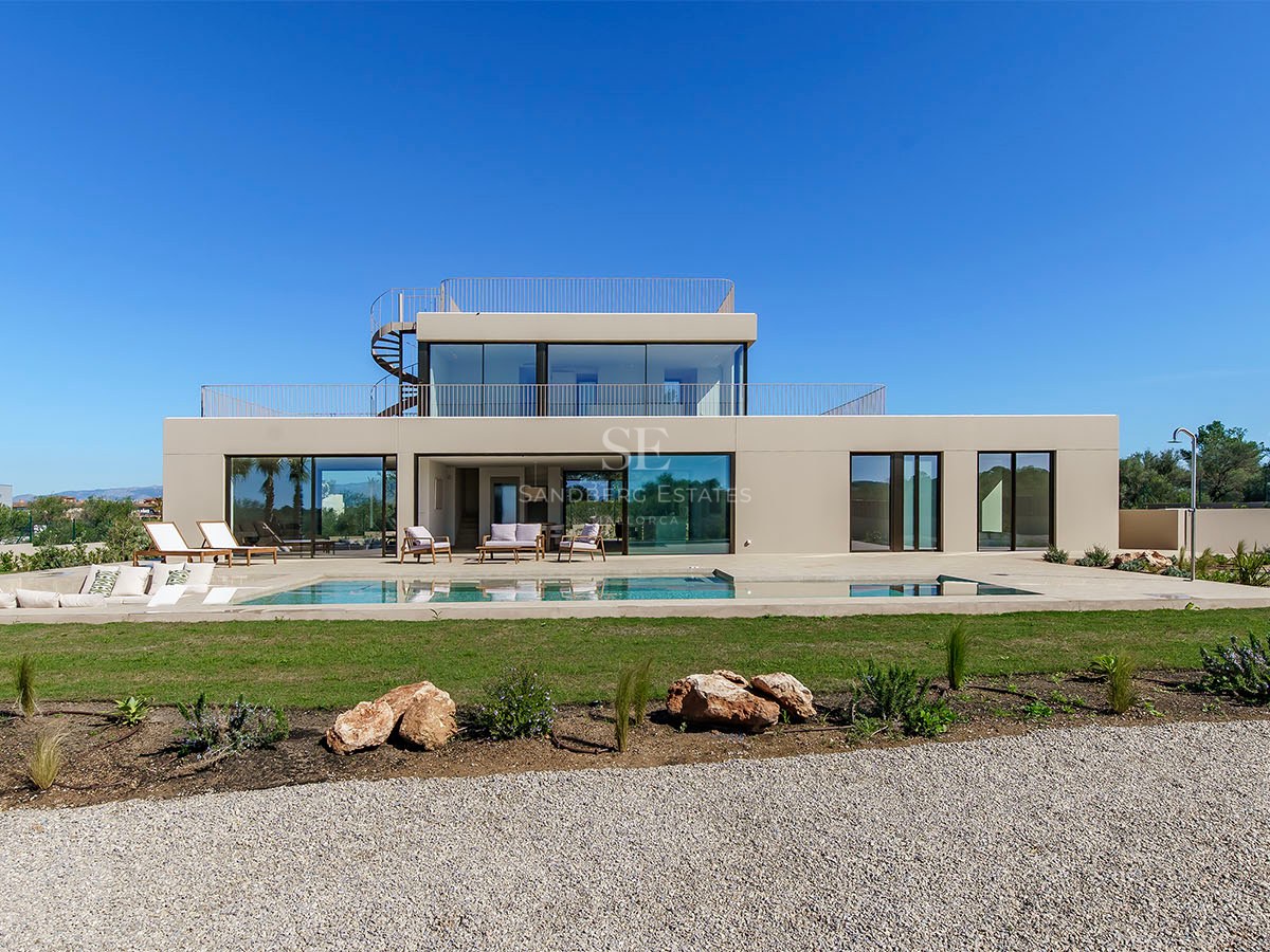 Villa moderne de deux étages avec grande piscine rectangulaire, baies vitrées et escalier extérieur en colimaçon.