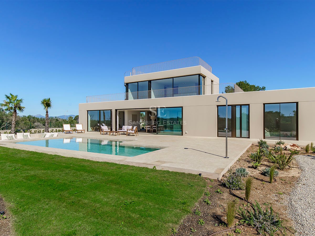 Façade d'une villa moderne de deux étages avec de grandes baies vitrées, piscine privée et jardin sous un ciel bleu.