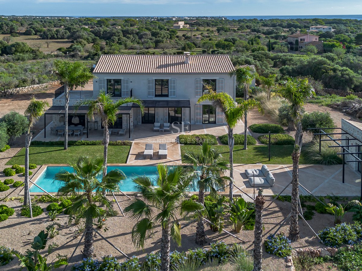 Vue aérienne d'une villa de luxe sur deux étages avec piscine, palmiers et mer Méditerranée à l'horizon.
