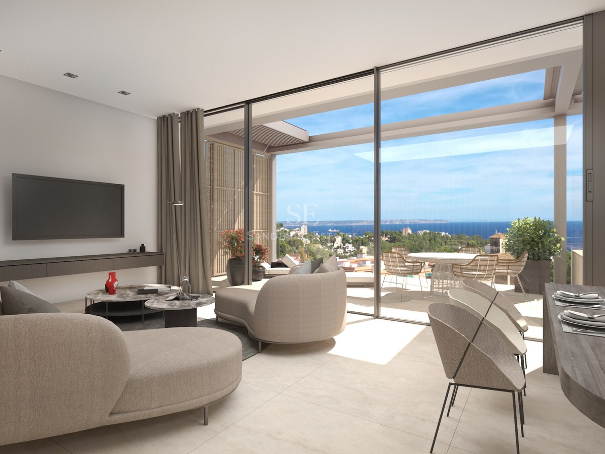Salon moderne lumineux avec canapés beiges incurvés et grandes baies vitrées ouvrant sur une terrasse face à la mer.