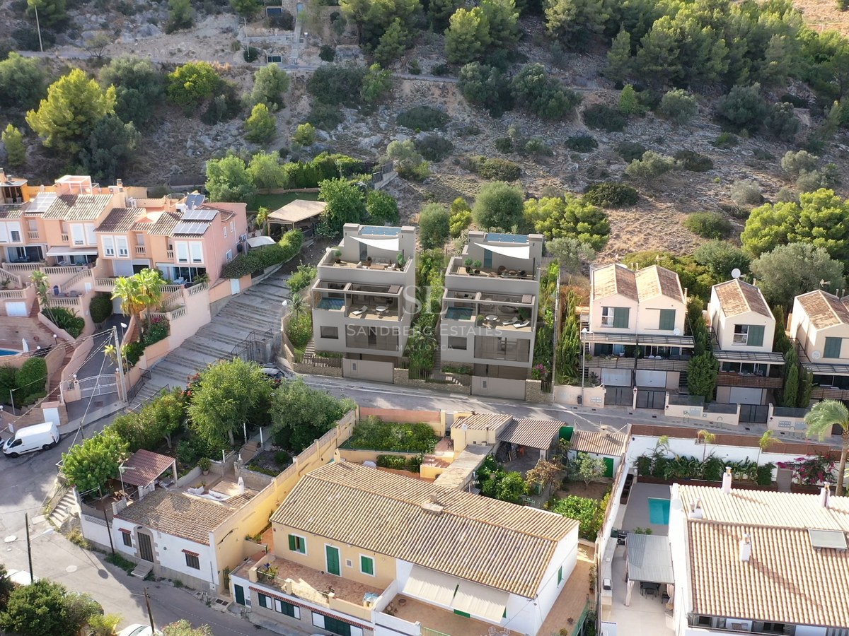 Vue aérienne de deux villas contemporaines grises entourées de maisons méditerranéennes traditionnelles en colline.