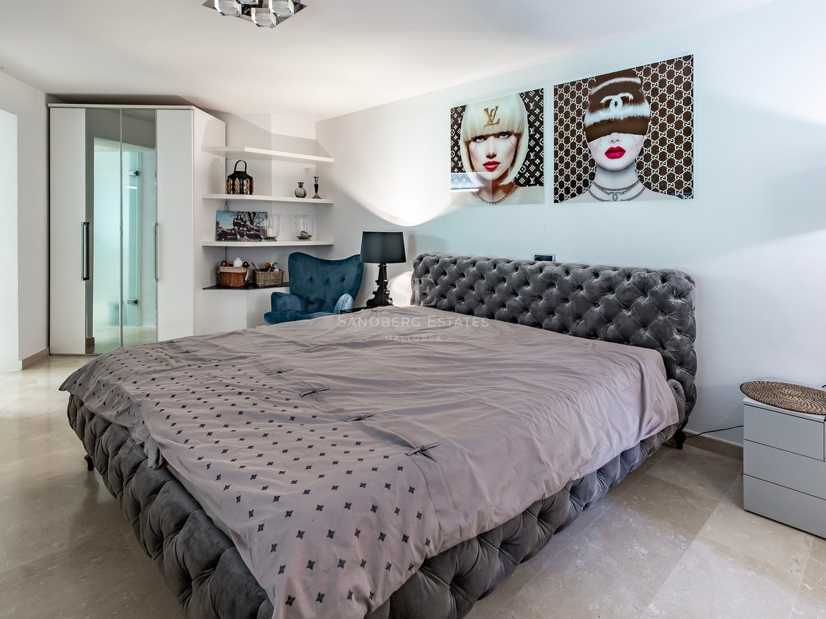 Chambre principale avec lit capitonné gris, sol en marbre poli et placards intégrés au design contemporain.
