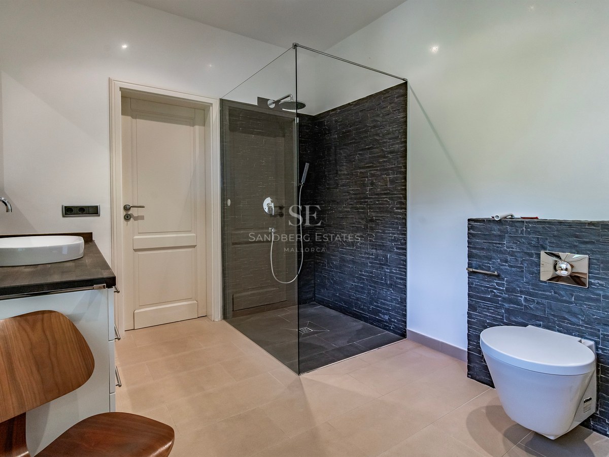 Salle de bain contemporaine avec douche à l'italienne en verre, murs en ardoise, WC suspendu et vasque à poser.