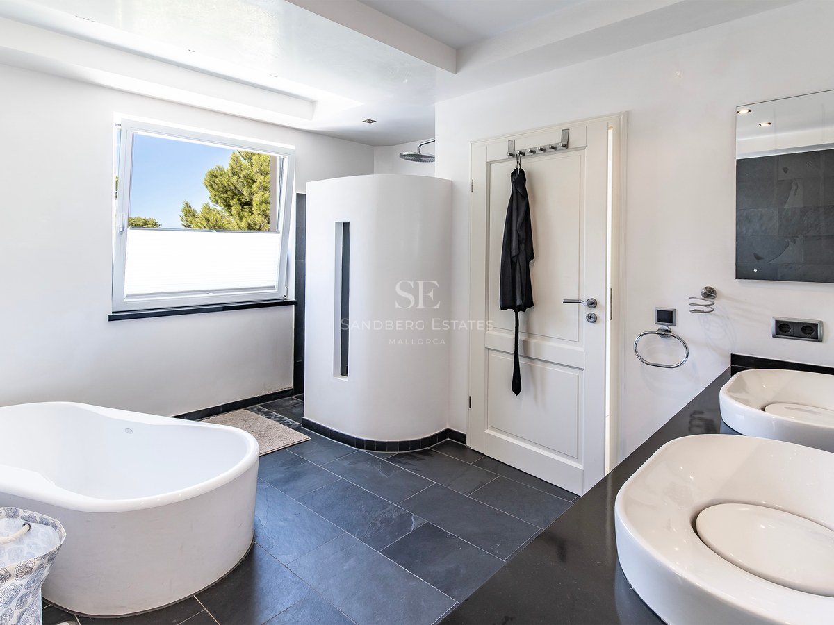 Salle de bains contemporaine avec baignoire en îlot, double vasque et sol en ardoise foncée.