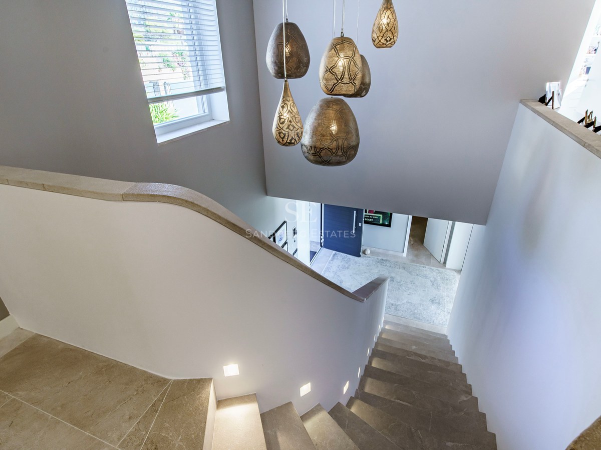 Escalera de piedra con luces LED integradas y lámparas de diseño vista desde arriba hacia la entrada.