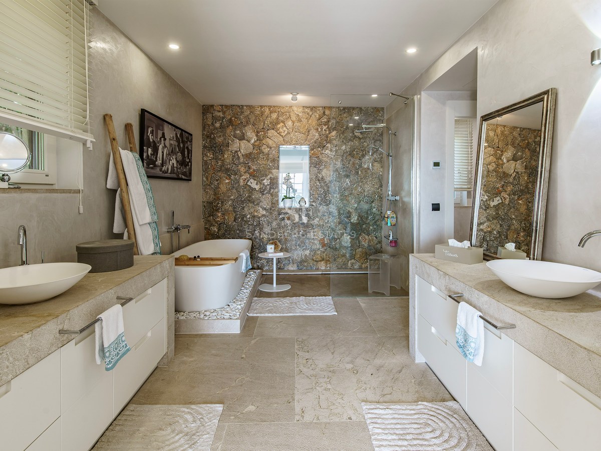 Baño principal contemporáneo con bañera exenta, pared de piedra natural, ducha italiana y lavabo doble.