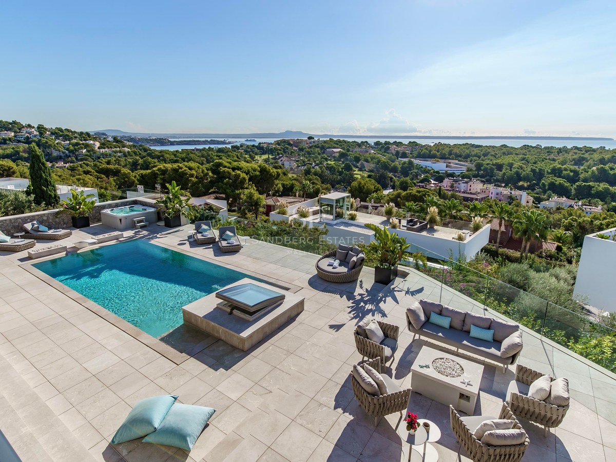 Terraza elevada con piscina turquesa, mobiliario de salón exterior y barandillas de cristal con vistas al Mediterráneo.