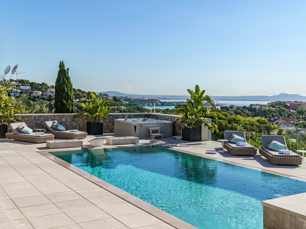 Piscina rectangular turquesa en terraza de piedra con jacuzzi y tumbonas frente al mar Mediterráneo.