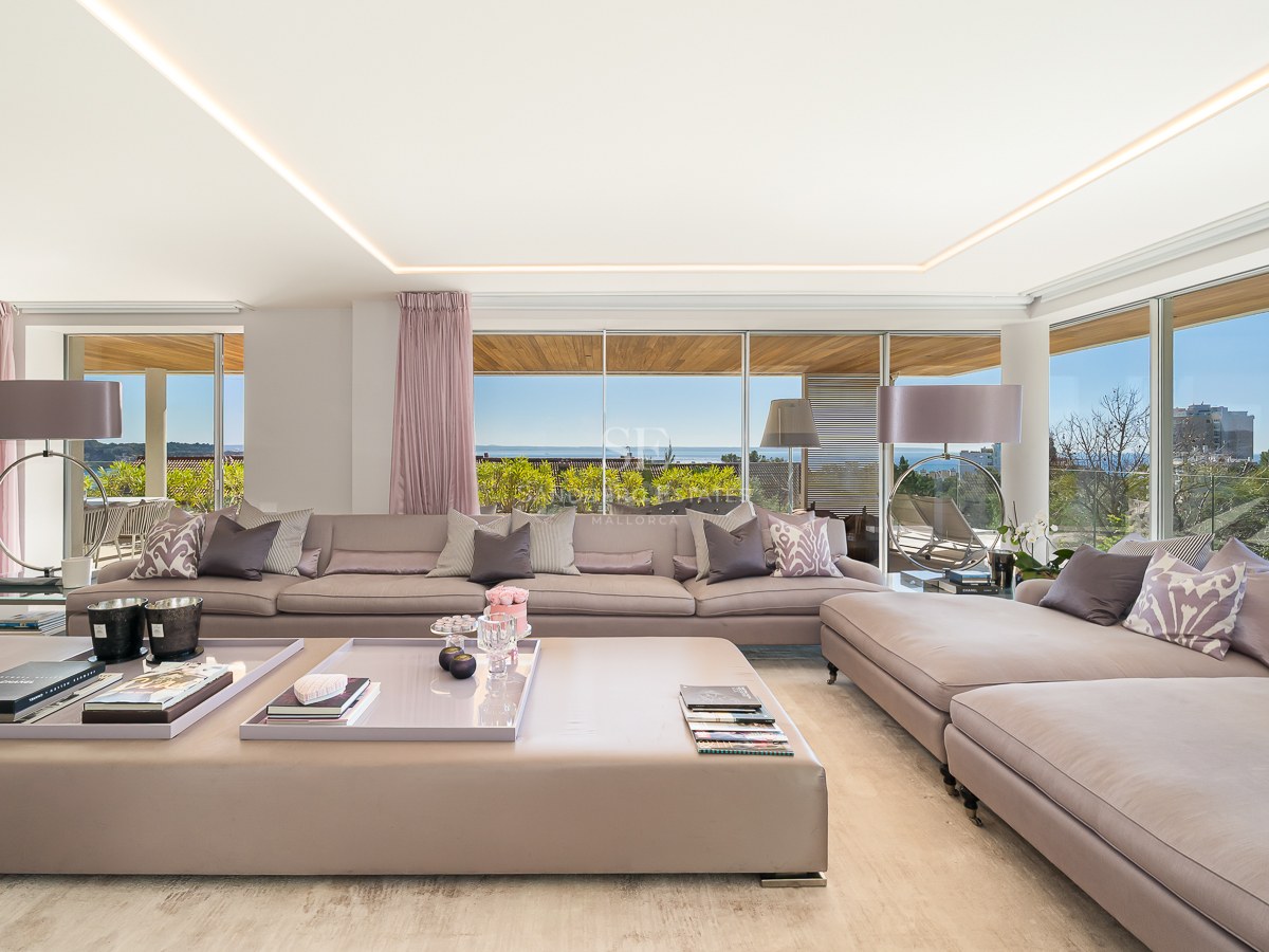Large mauve modular sofa in a bright living room with floor-to-ceiling windows overlooking the Mediterranean sea.