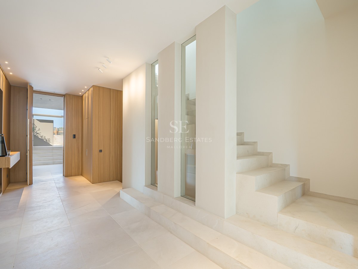 Couloir moderne avec sols en pierre crème, escalier en pierre minimaliste et boiseries en chêne clair.