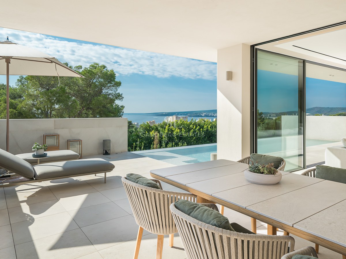 Terrasse moderne avec coin repas, chaises longues et piscine à débordement donnant sur la mer et la pinède.