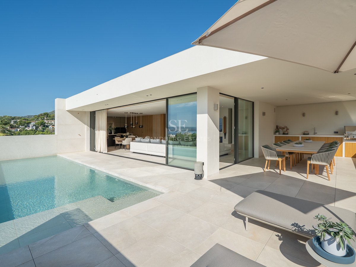 Terrasse de villa moderne avec piscine à débordement, chaises longues, salle à manger extérieure et espace de vie ouvert.
