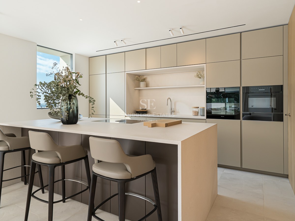 Cuisine moderne minimaliste avec un grand îlot central, des tabourets design et des armoires lisses aux tons terreux.