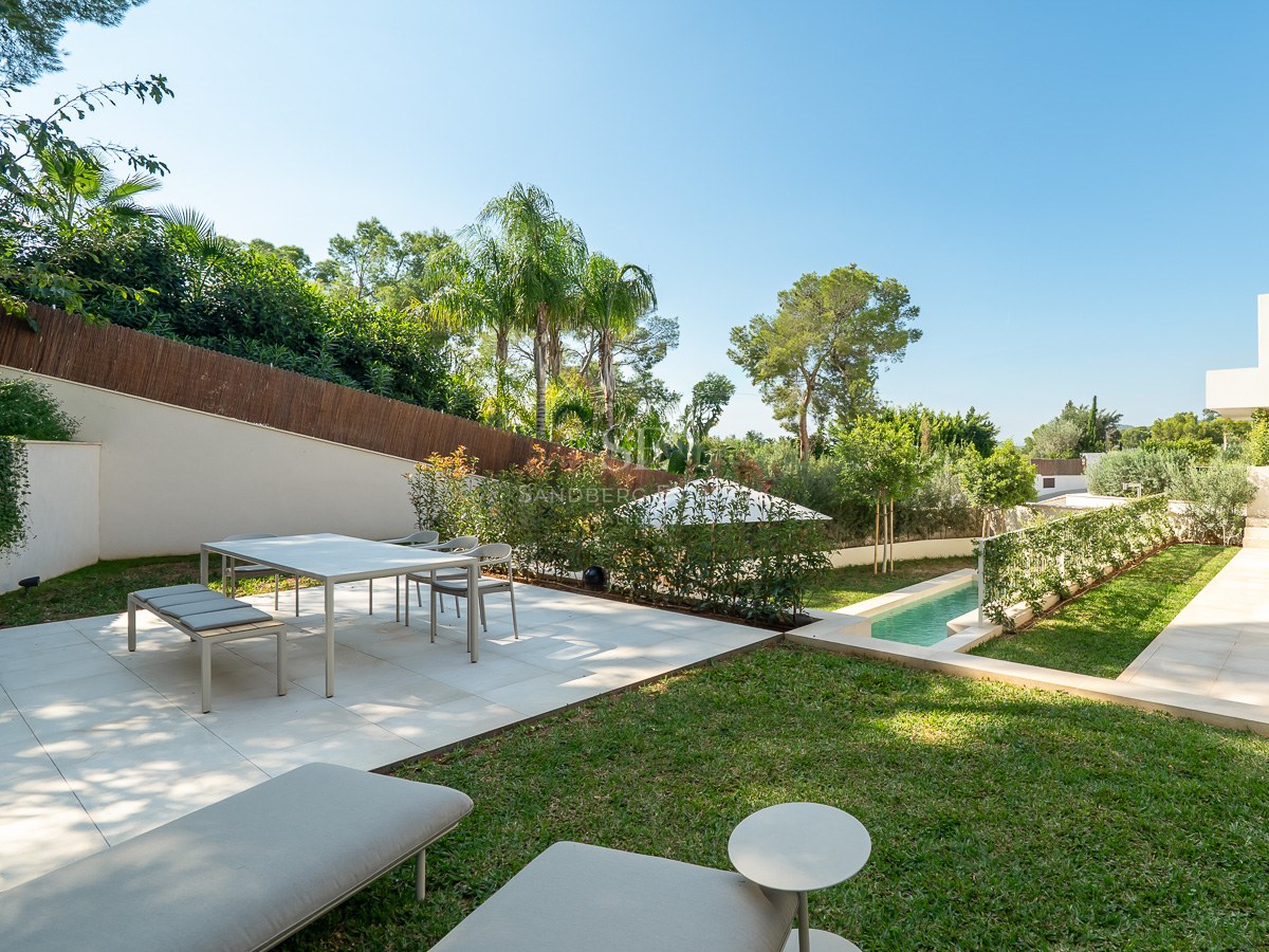 Terrasse moderne avec coin repas, barbecue et piscine entourée d'une végétation luxuriante et de palmiers.
