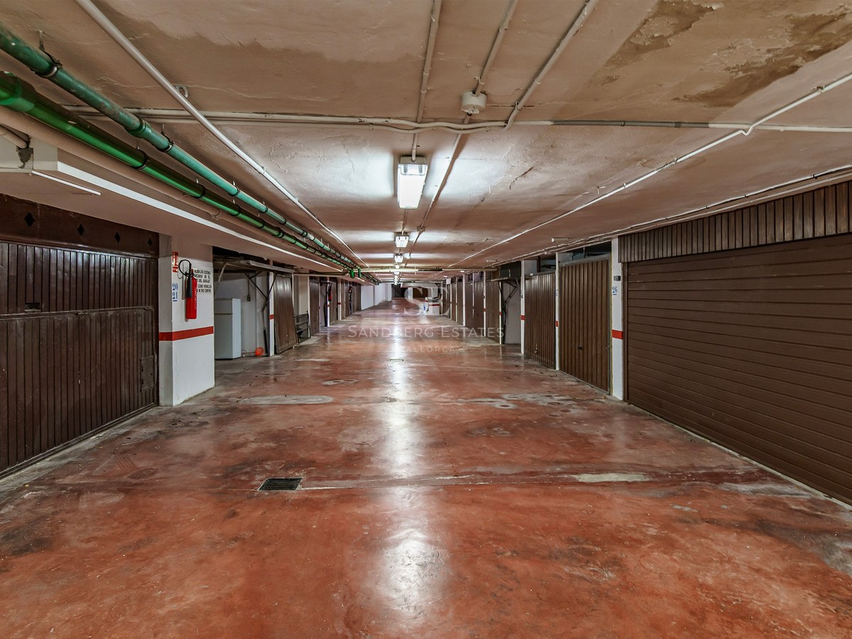 Underjordisk garagegång med rött betonggolv och bruna garageportar på båda sidor.