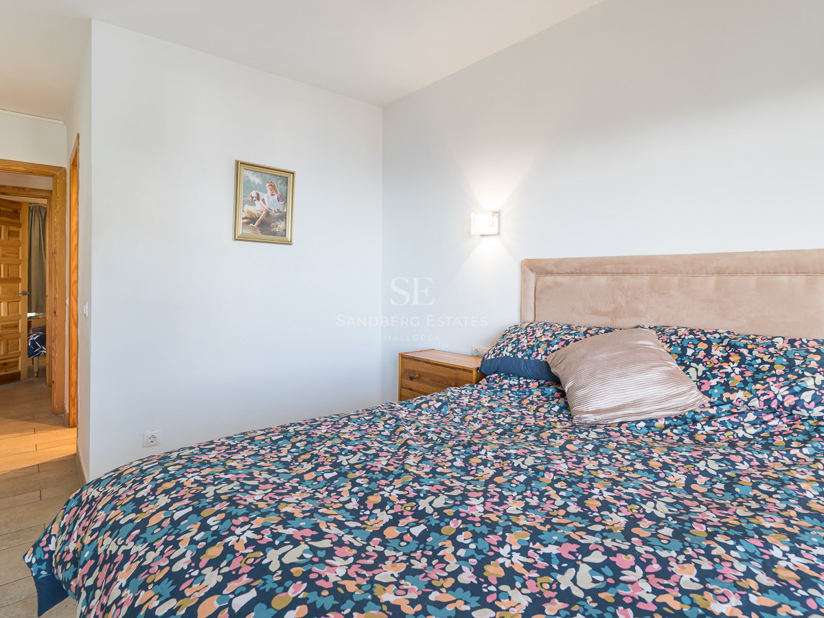 A bedroom featuring a large bed with a floral duvet, upholstered headboard, and rustic paneled wooden doors.