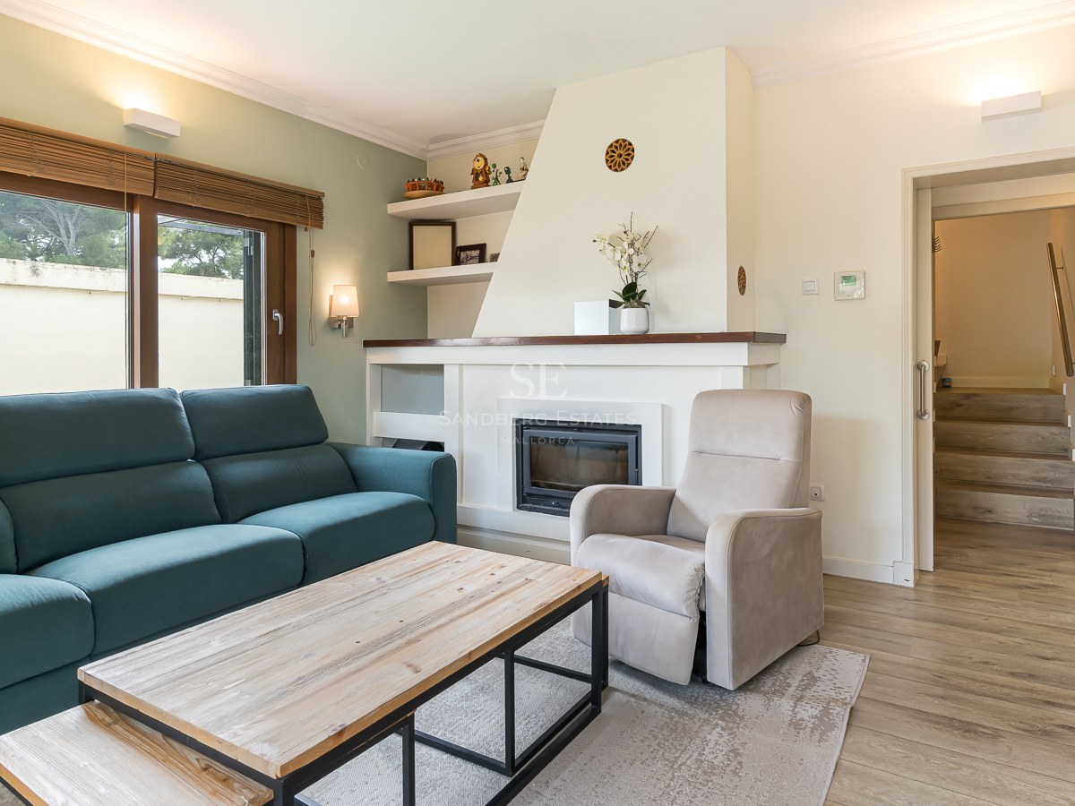 Modern living room with a teal sofa, white built-in fireplace, wooden coffee table, and beige armchair.