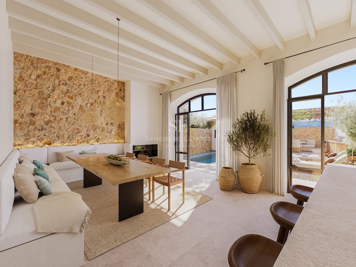 Elegant dining area featuring a natural stone wall, wooden beams, and large arched doors opening to a swimming pool.