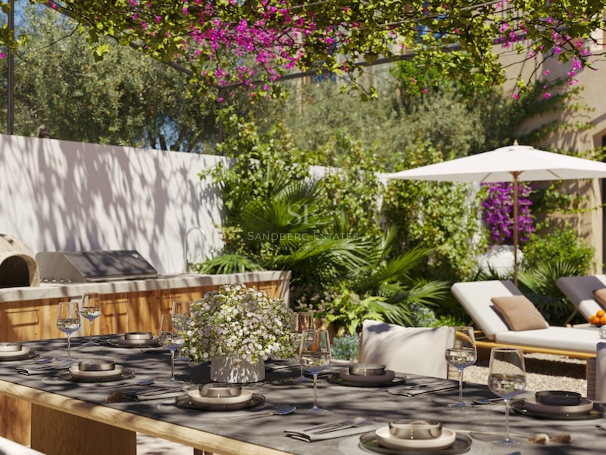 An outdoor dining table set under a bougainvillea pergola, featuring an outdoor kitchen and sun loungers in a garden.