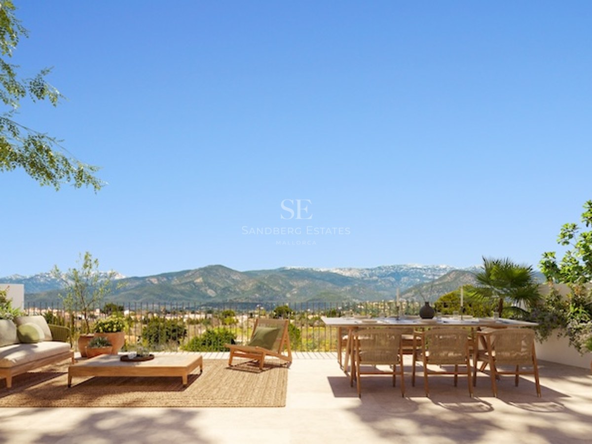 Spacious outdoor terrace with wooden dining set, lounge furniture, and panoramic views of distant mountains.