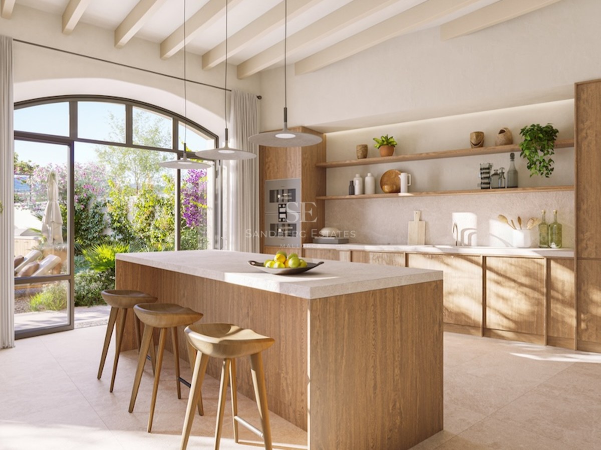 Bright kitchen featuring a large wooden island, designer stools, and arched doors opening to a sunny garden.