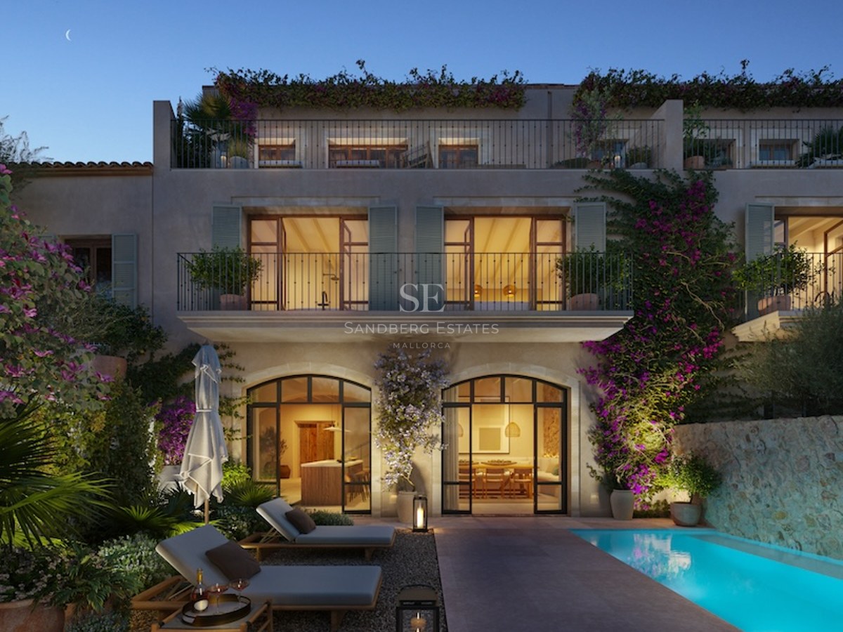 Luxury villa at twilight featuring a glowing blue pool, sun loungers, stone walls, and climbing bougainvillea plants.
