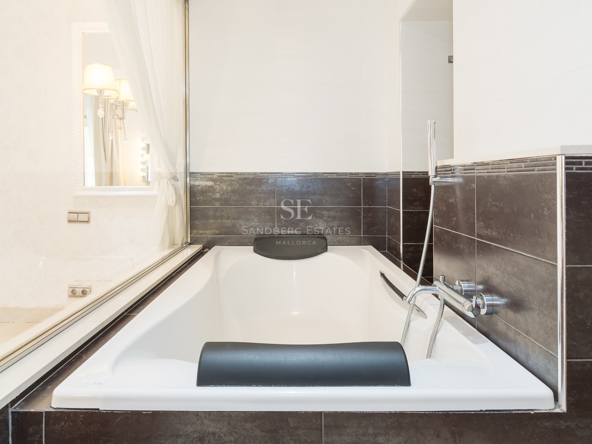 Baignoire blanche avec appuie-tête noirs et carrelage marron foncé dans une salle de bain moderne.