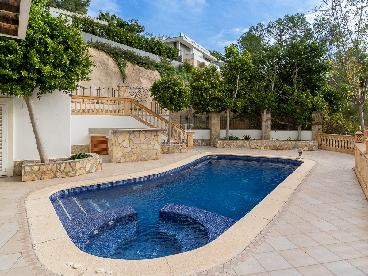 Piscine bleue avec sièges intégrés sur une terrasse carrelée entourée de balustrades et d'arbres.