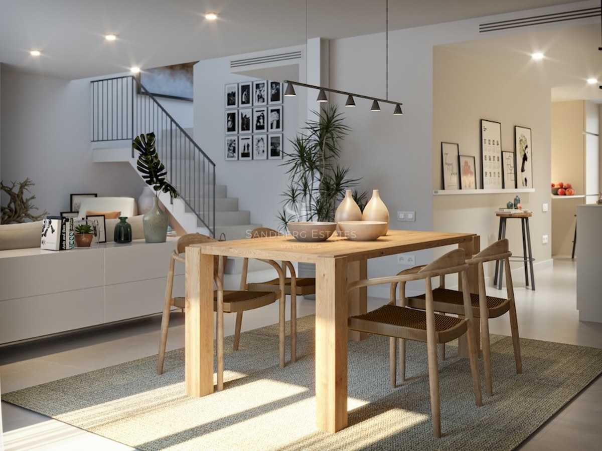 Contemporary dining area with a light wood table, four woven chairs on a grey rug, and a modern staircase in the background.