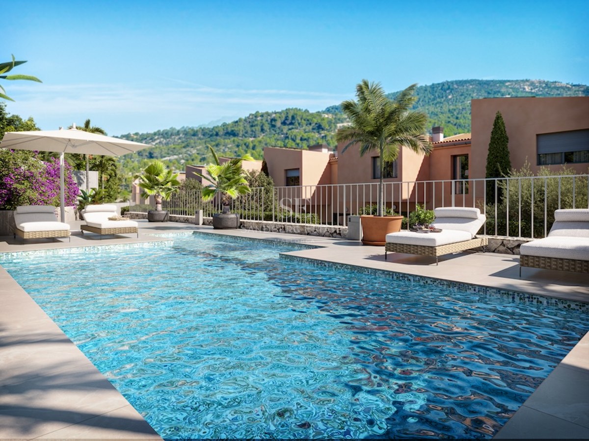 Turquoise swimming pool with sun loungers and palm trees overlooking lush green mountains under a blue sky.