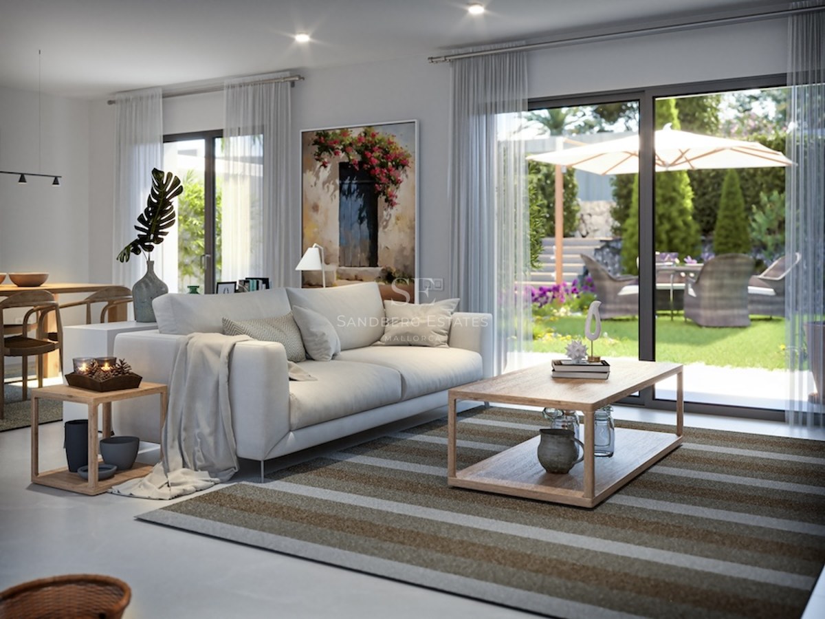 Contemporary living room featuring a white sofa and large sliding glass doors opening to a lush sunlit garden.