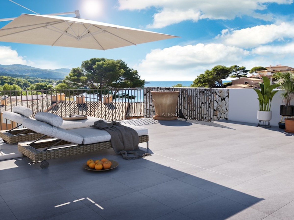 Terraza soleada con tumbonas, sombrilla grande y vistas panorámicas al mar y la montaña.