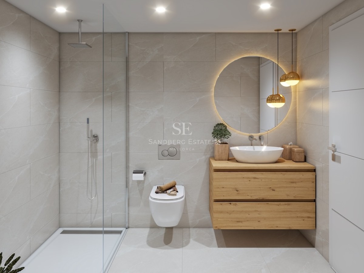 Modern bathroom featuring a glass shower, wooden vanity, backlit circular mirror, and beige marble-effect tiles.