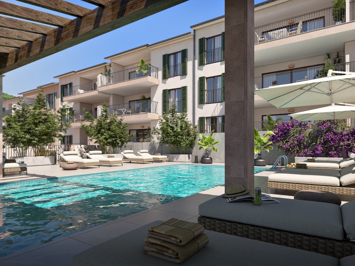 Modern turquoise pool area with sun loungers, umbrellas, and a wooden pergola next to a Mediterranean-style building.