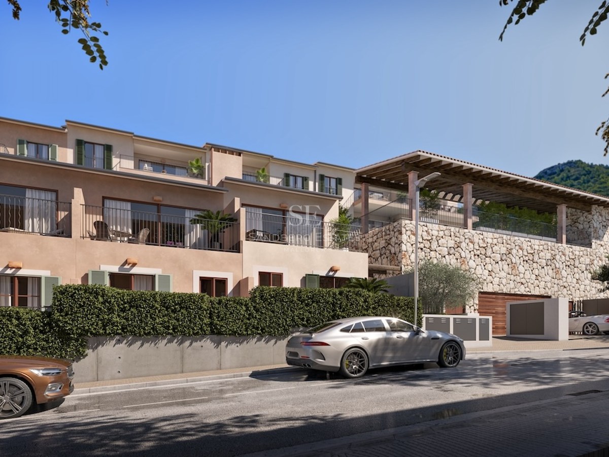Vista exterior de una villa mediterránea moderna con muros de piedra, balcones y setos verdes bajo un cielo azul.