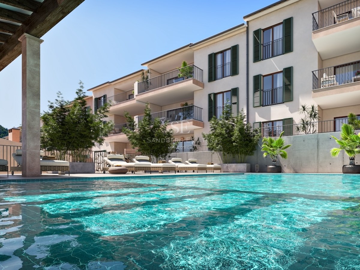 Gran piscina turquesa con tumbonas frente a un edificio de apartamentos con persianas verdes y balcones.
