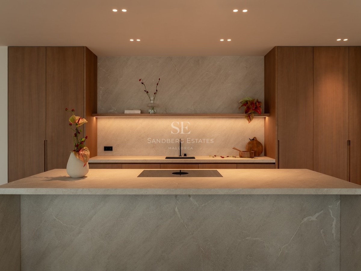 Modern kitchen featuring a large stone waterfall island, warm wood cabinetry, and integrated LED ambient lighting.