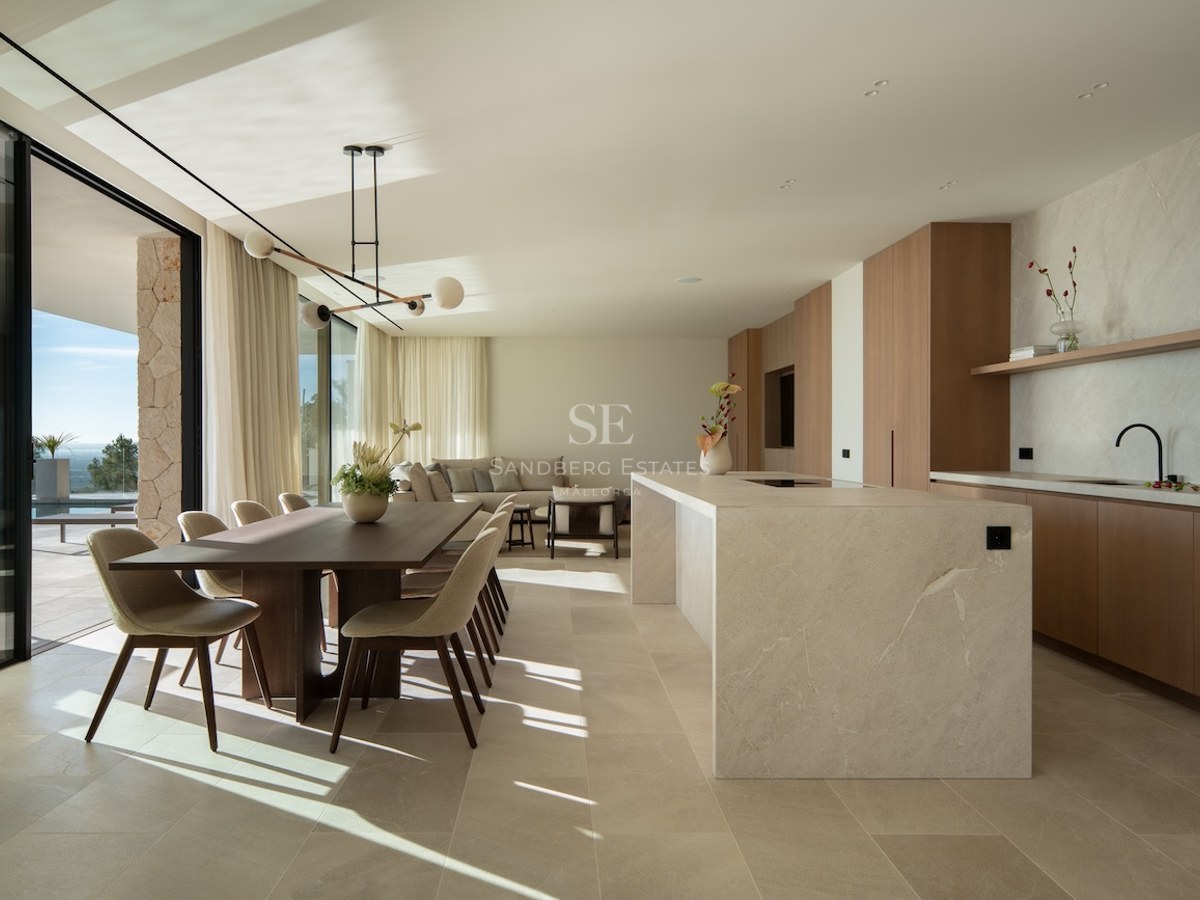 Spacious open-concept room featuring a stone kitchen island, wooden dining table, and floor-to-ceiling terrace doors.