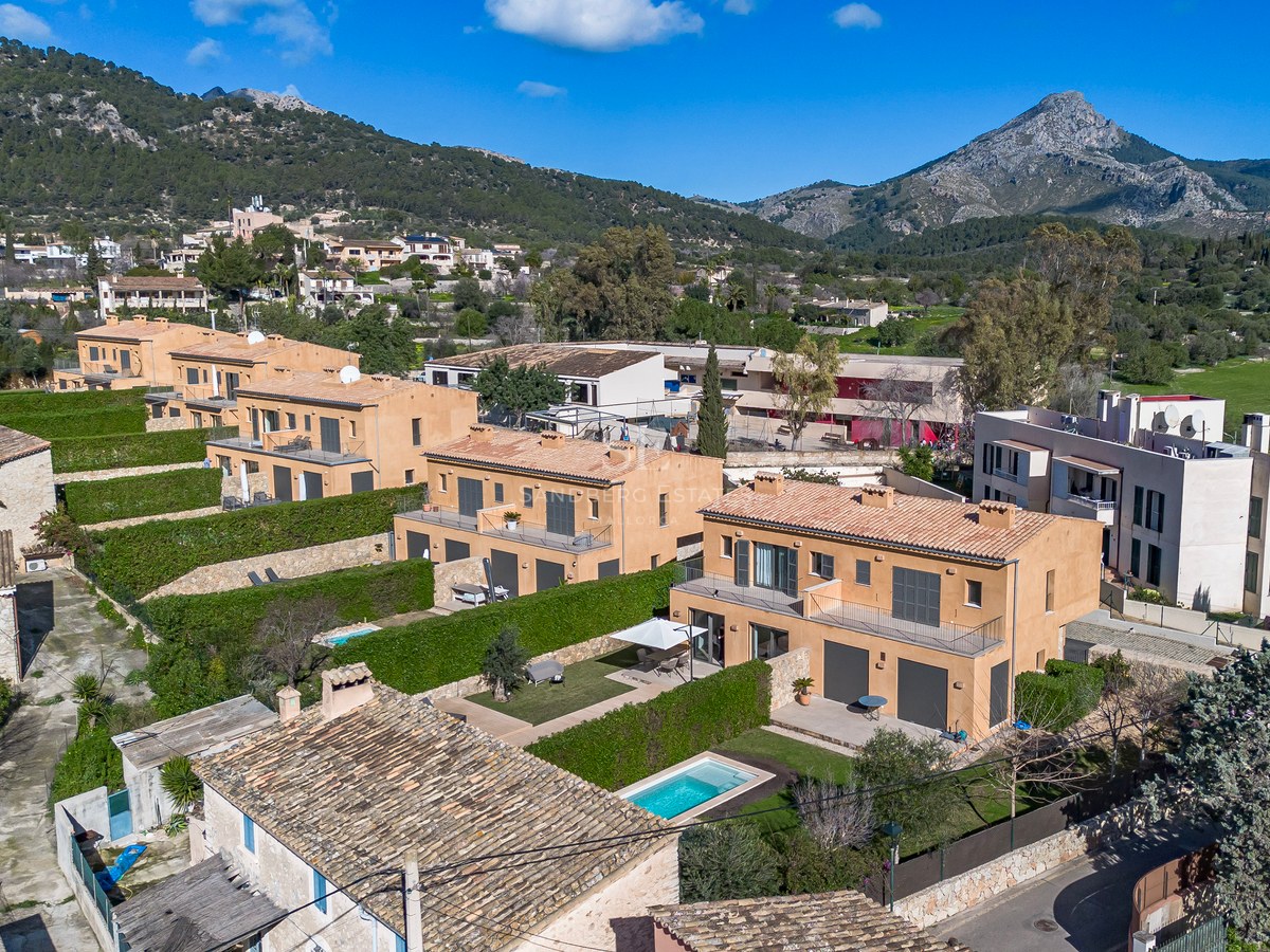 Vue aérienne de villas couleur terre cuite avec piscines privées et haies vertes sur fond de montagnes.