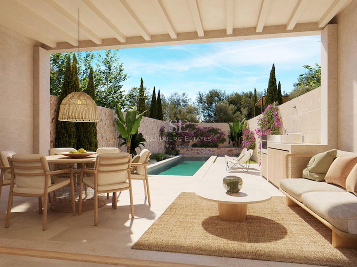 A covered terrace with a dining set, sofa, and outdoor kitchen, overlooking a long swimming pool and lush garden.