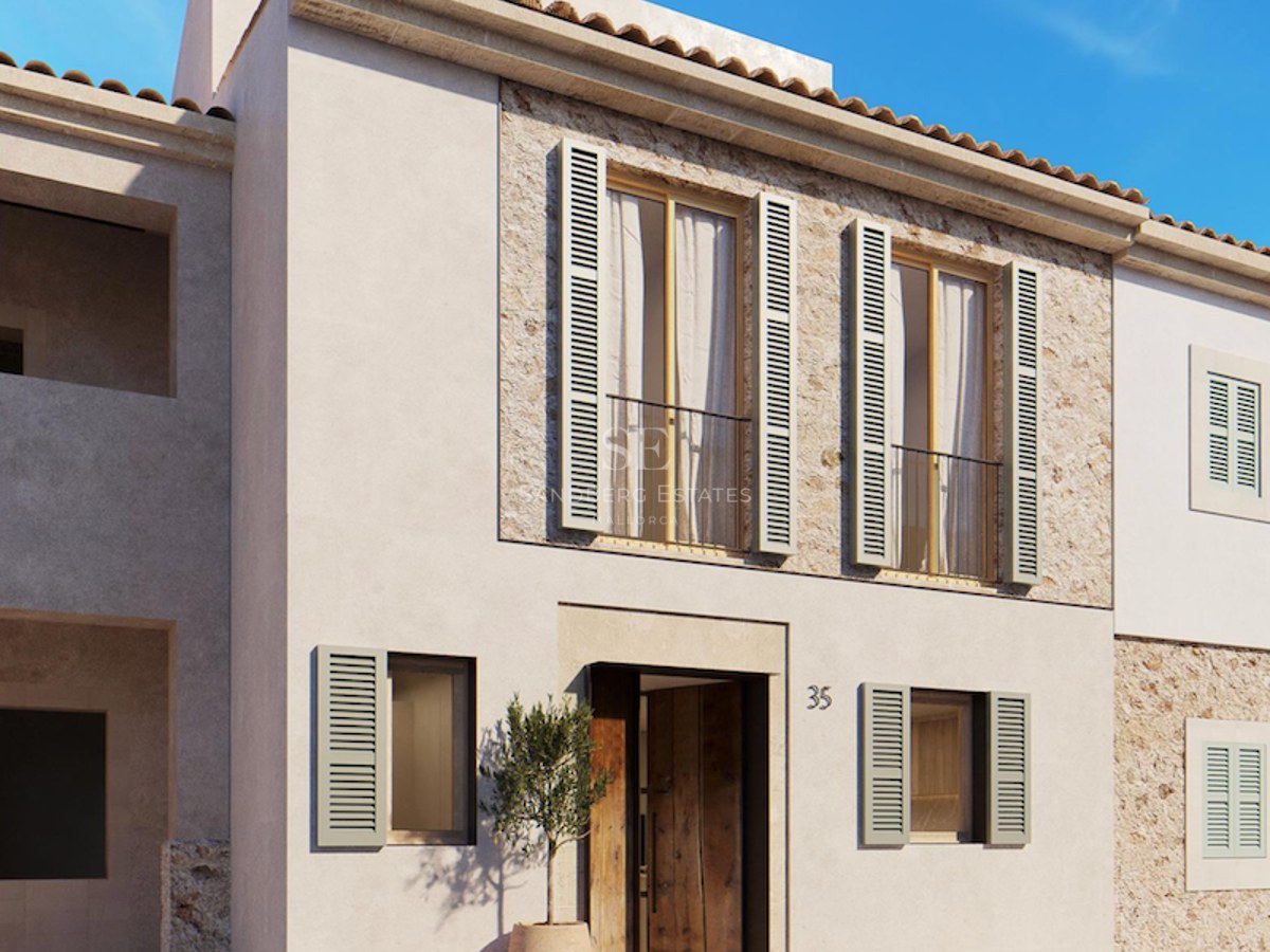 Beige stucco building with sage green shutters, natural stone accents, and a wooden door under a clear blue sky.