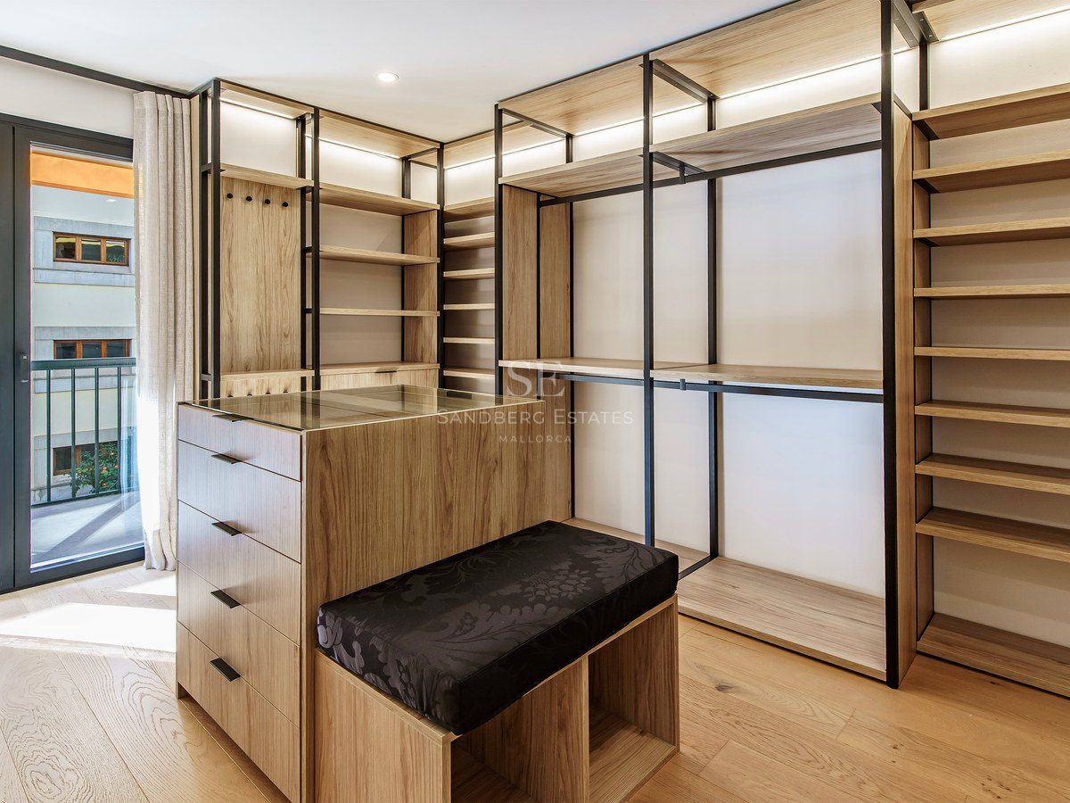 Modern walk-in closet with light wood shelving, black metal frames, a central island, and balcony access.