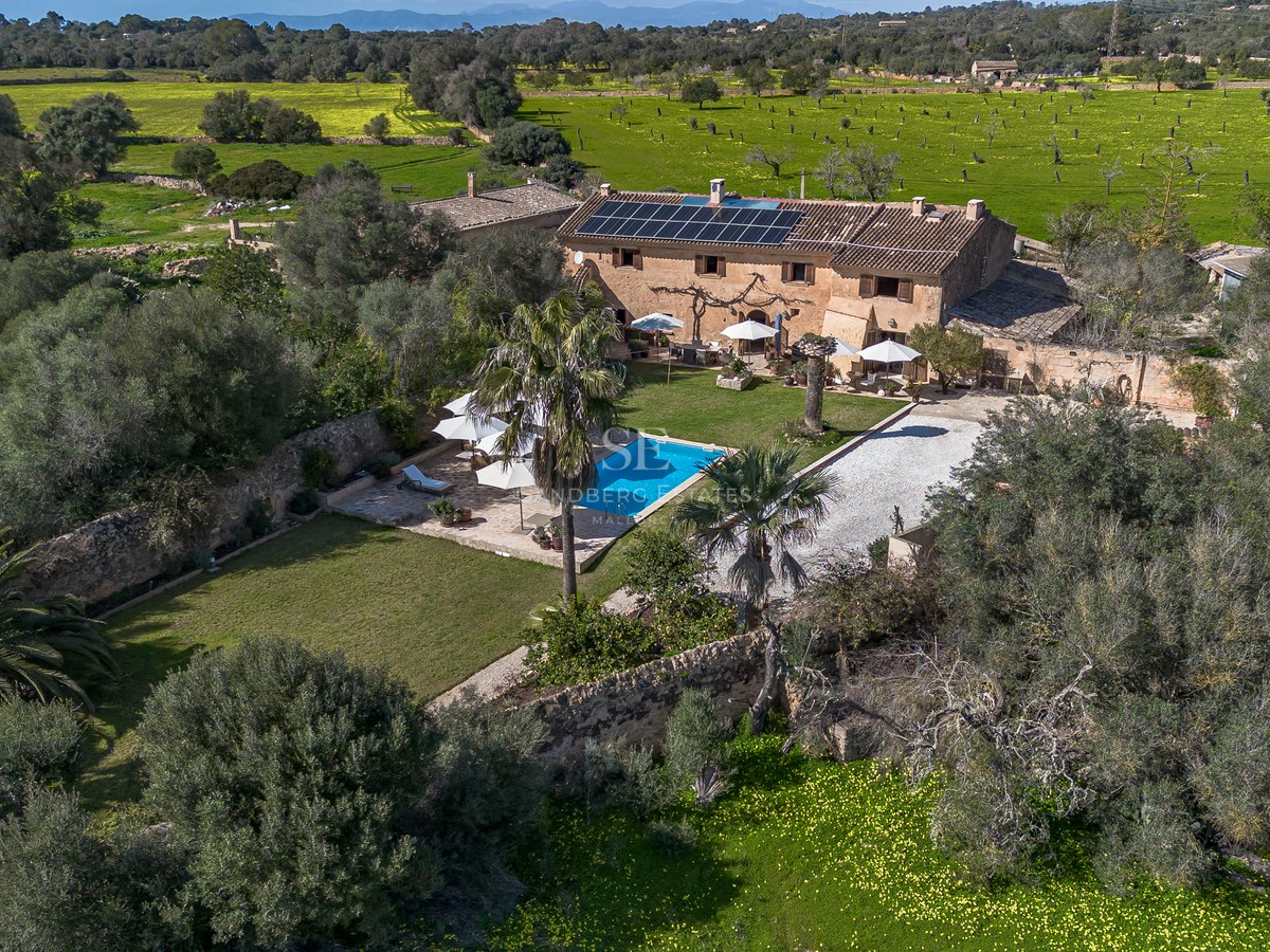 Luftaufnahme einer traditionellen Steinfinca mit Swimmingpool, Sonnenkollektoren und weitläufigen Gärten auf Mallorca.
