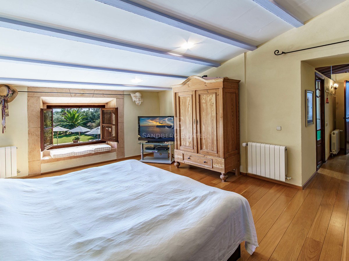 Gemütliches Schlafzimmer mit Holzböden, rustikalem Schrank und Fenster mit Blick auf einen üppigen Garten.