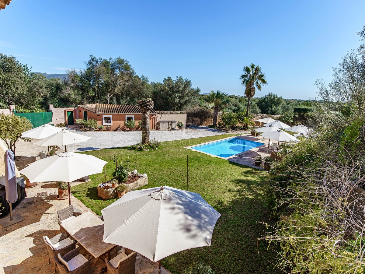 Rechteckiger Pool umgeben von grünem Rasen, Sonnenschirmen und einer Steinterrasse in einem mediterranen Anwesen.