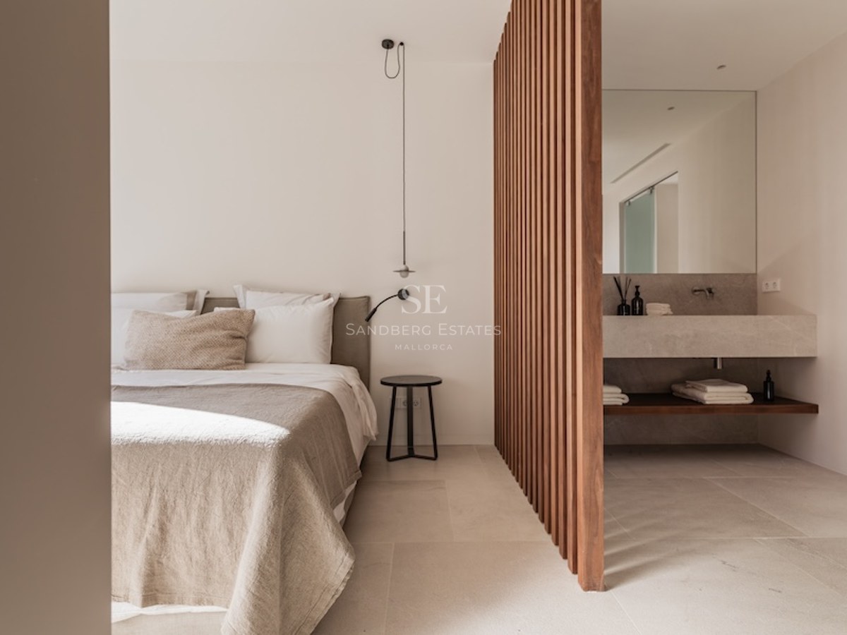 Minimalist beige bedroom separated from a stone vanity by vertical wooden slats.